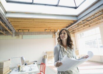 Businesswoman holding blueprints in new office 497325699 5b9ac78146e0fb0025297b7f.jpg
